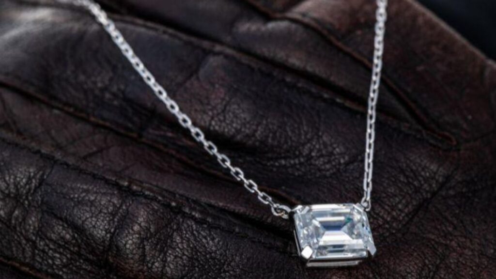 A stunning emerald-cut diamond pendant necklace, resting on a luxurious leather surface.