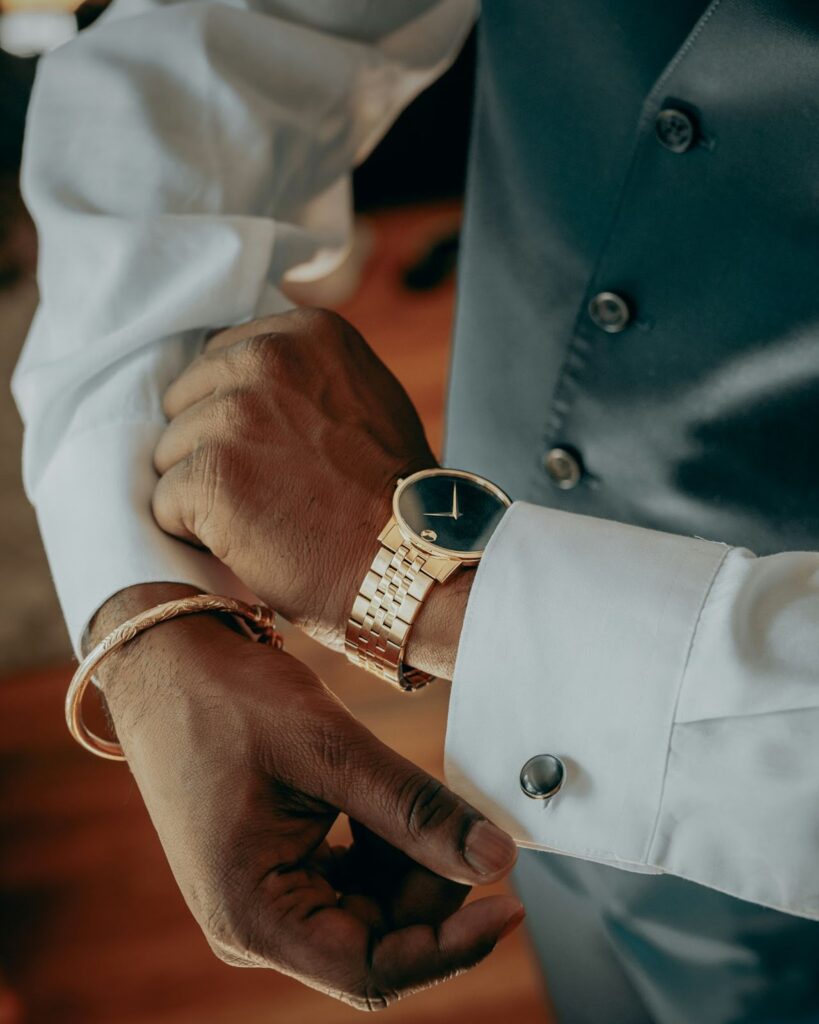 A man adjusting his cufflinks and checking the time on his gold watch, preparing for a special occasion.