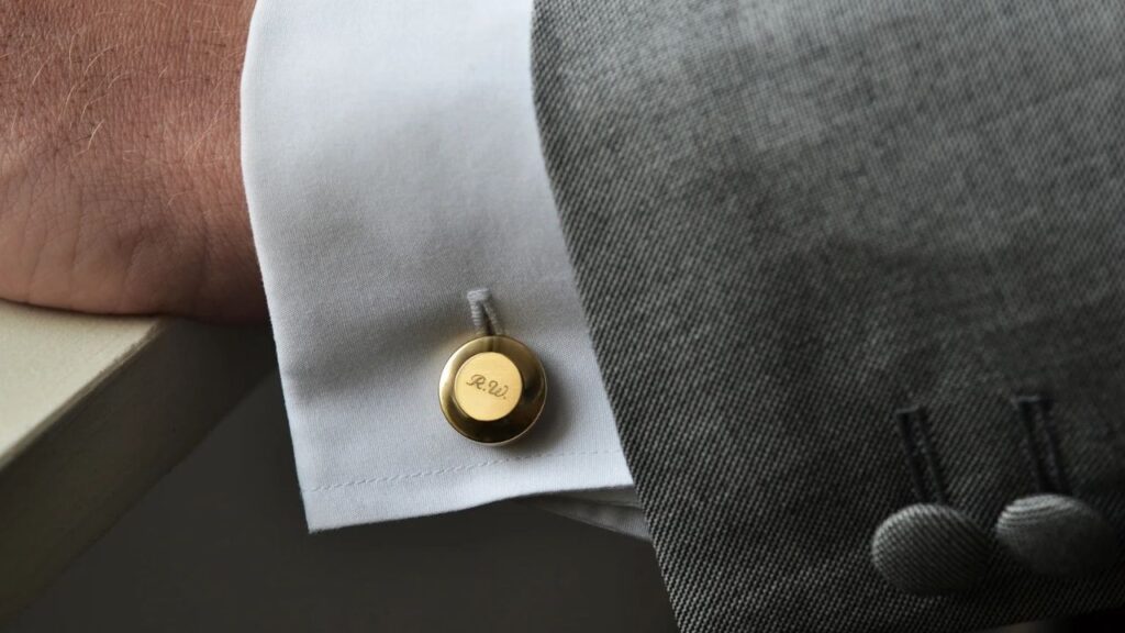 Monogrammed gold cufflinks adding a touch of elegance to a crisp white shirt cuff.