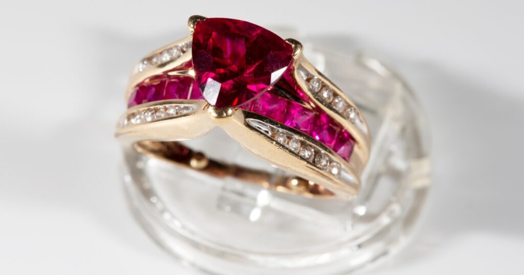 A yellow gold ring with a ruby center stone and diamond and ruby accents.