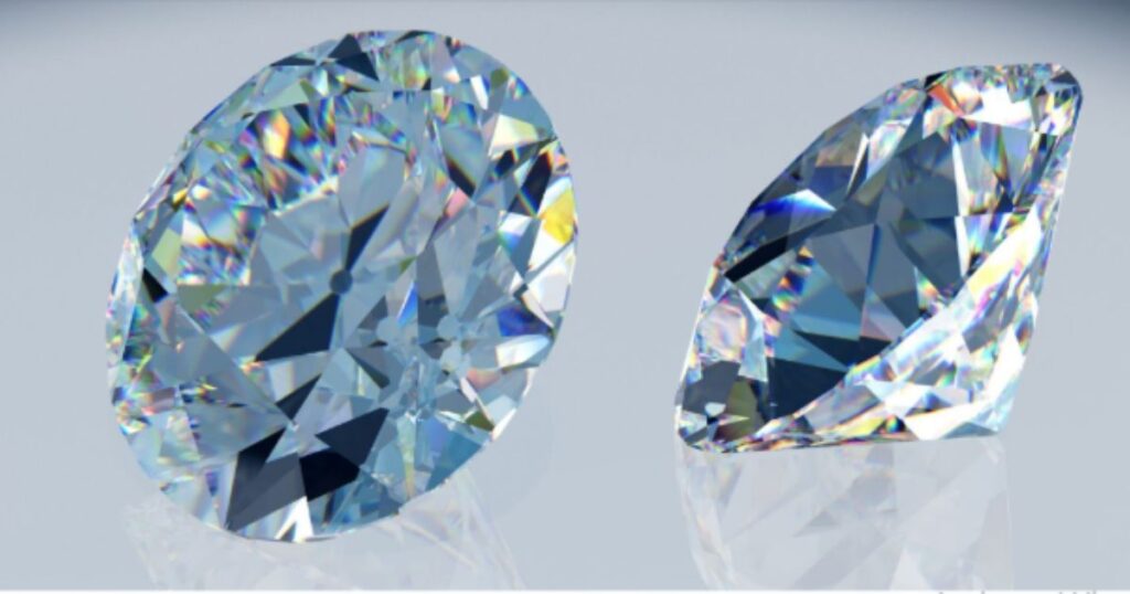 Two sparkling, bluish-tinted diamonds, one oval and one round, displayed on a light gray, reflective surface.