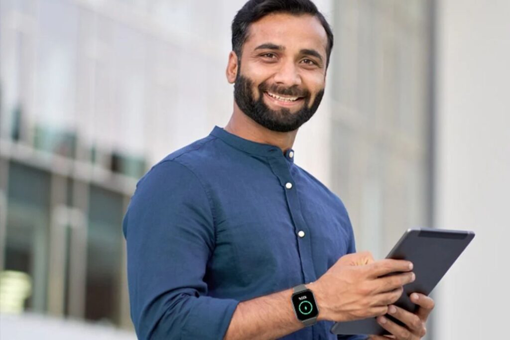 A smiling man with a tablet wearing a smartwatch, conveying Professional watches and impressions.