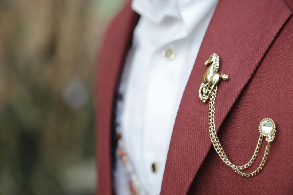A person in a maroon suit jacket with a gold horse-shaped lapel pin, showcasing Jewelry to impress boss from Wulf Diamond Jewelers.
