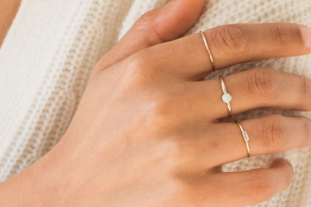 A close-up of a hand wearing three delicate gold rings, highlighting Jewelry to impress boss from Wulf Diamond Jewelers.