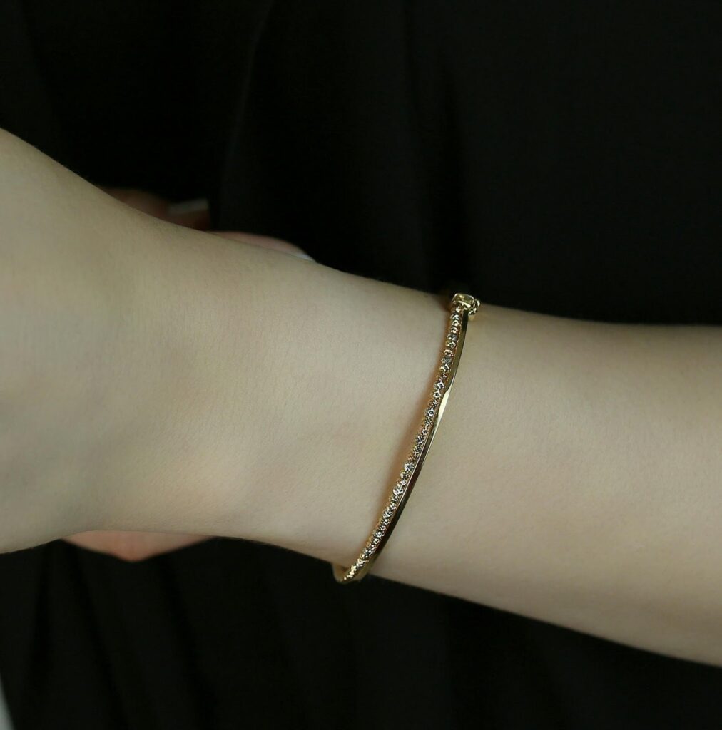 A hand displaying a delicate gold bracelet with small diamonds, highlighting Jewelry to impress boss from Wulf Diamond Jewelers.