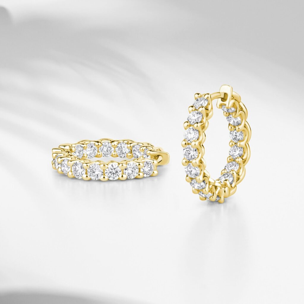 A person's hand wearing a delicate gold ring with a green stone, showcasing Professional Jewelry For Work.
