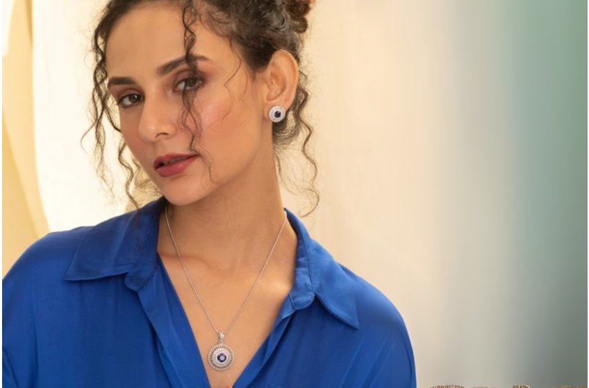 A person with curly hair wearing a necklace and stud earrings, suggesting Office Jewelry Essentials.