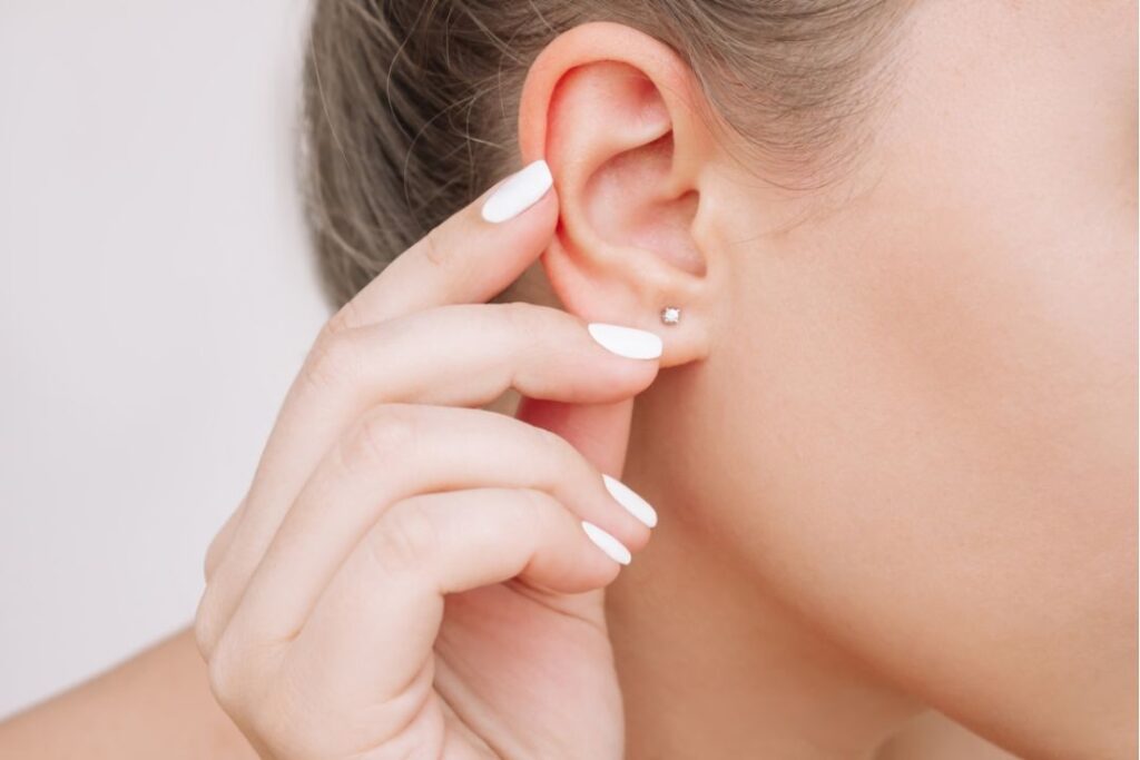A person's ear adorned with a delicate star and moon earring, showcasing Business Jewelry from Wulf Diamond Jewelers.