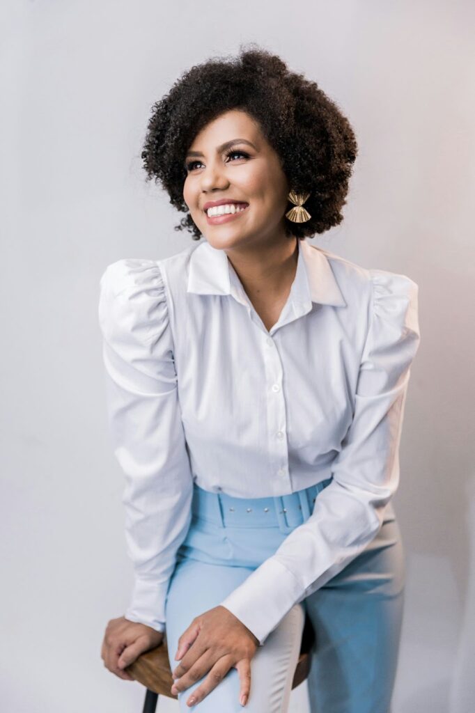 A young, smiling professional woman with voluminous curly hair and golden earrings, perfect for Business Jewelry.