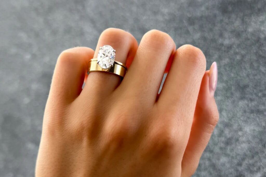 A person's hand adorned with a large oval diamond ring, showcasing Diamond Jewelry Essentials from Wulf Diamond Jewelers.