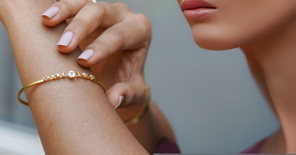 Close-up shot of a model's hand and wrist wearing a delicate gold bracelet with small, sparkling stones, a piece of minimalist vacation jewelry by Wulf Diamond Jewelers.