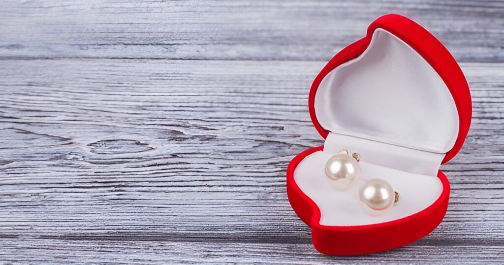 
A heart-shaped box holds pearl earrings, representing Wulf Diamond Jewelers' Tropical jewelry trends for a special gift.