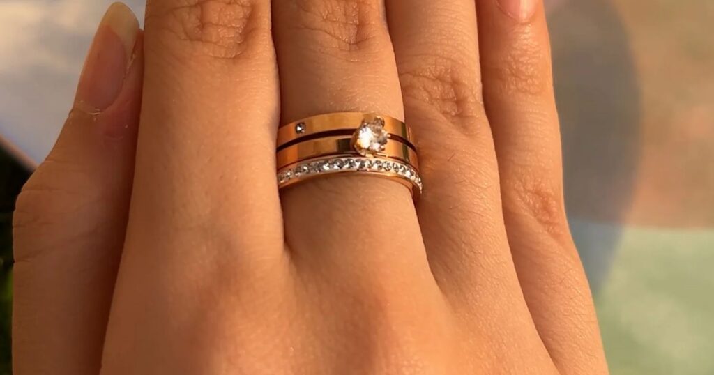 Close-up shot of a hand wearing three stacked rings in rose gold, part of the minimalist vacation jewelry line by Wulf Diamond Jewelers.