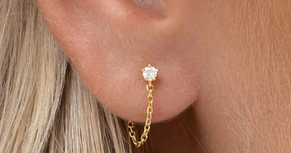 A delicate gold chain earring with a diamond stud, part of Wulf Diamond Jewelers' Beach jewelry essentials collection.