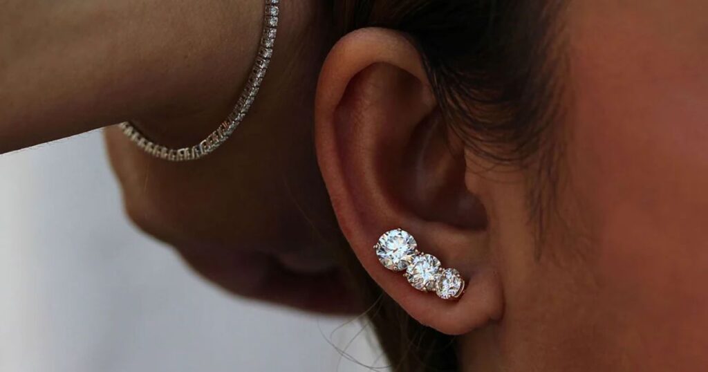 A person's ear with a diamond ear crawler earring and a diamond bracelet, highlighting Wulf Diamond Jewelers' Wedding jewelry for destination weddings.