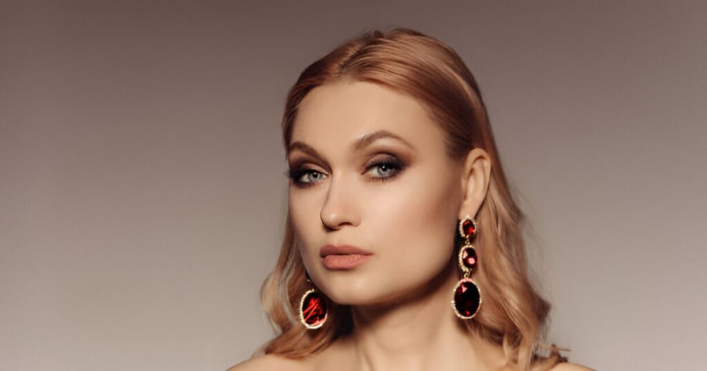 A blonde woman models red gem earrings, showcasing Stylish jewelry for holidays