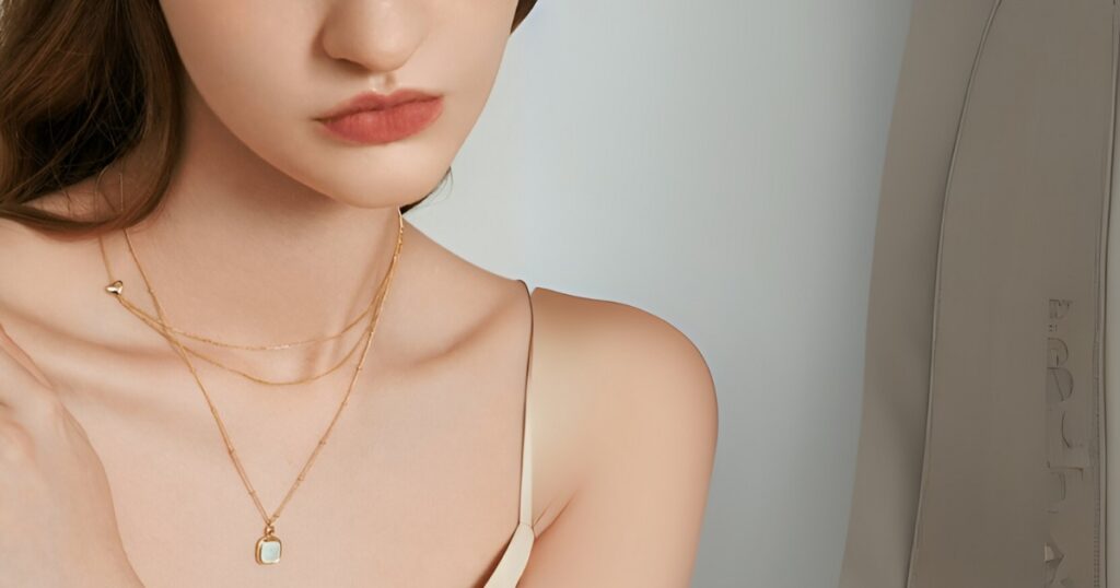 A young woman with a long neck and shoulder, adorned with dainty lightweight travel necklaces by Wulf Diamond Jewelers.