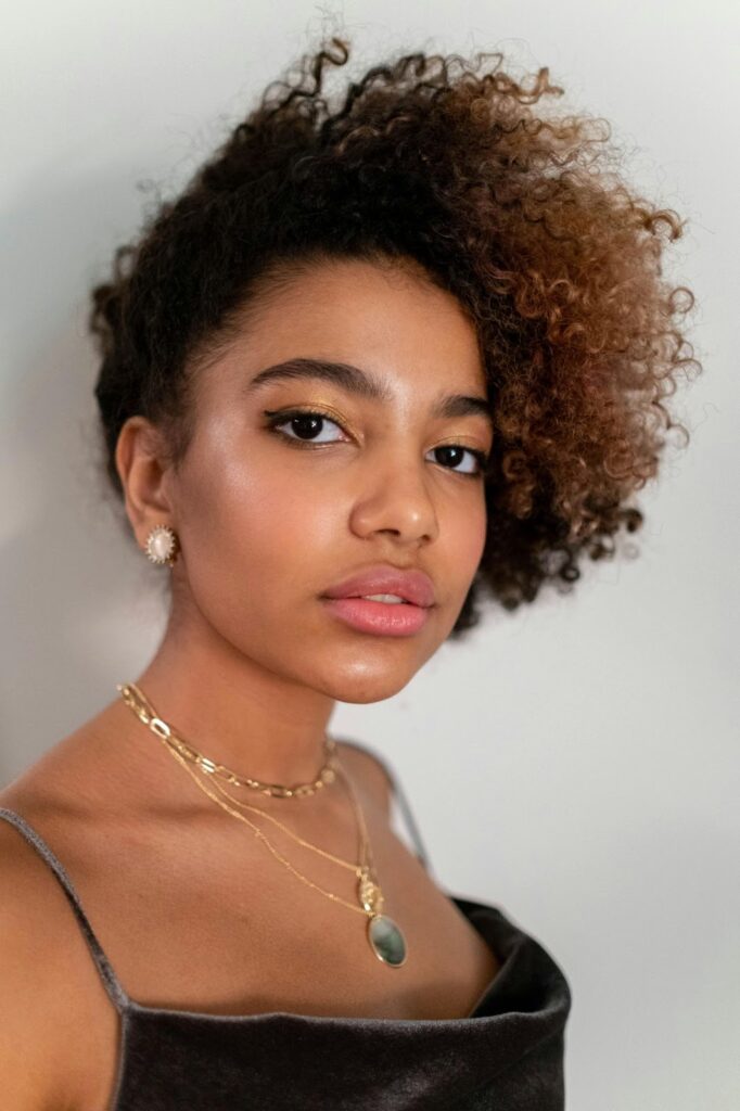 A young woman with a long neck and shoulder, adorned with dainty lightweight travel necklaces by Wulf Diamond Jewelers.